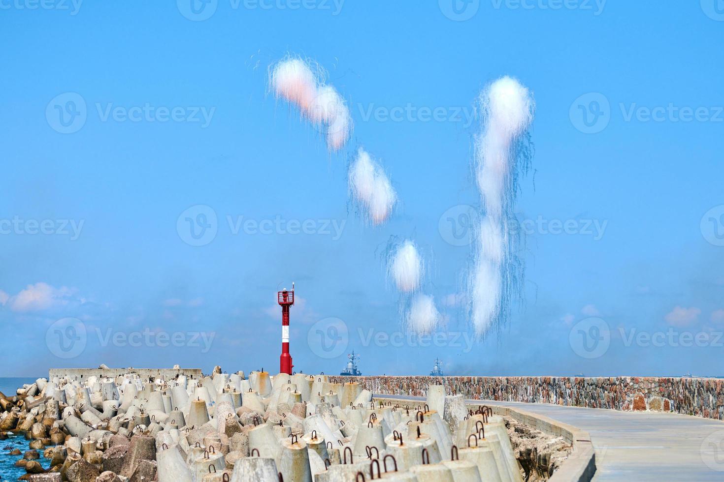 witte koolstofvezelwolken in de blauwe lucht die zeevernietigers verbergen voor anti-scheepsraketten, militaire show foto