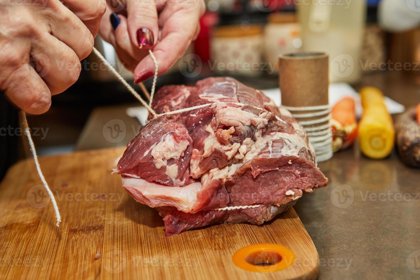 chef banden de rundvlees met touw en bereidt zich voor het voor bakken in de oven foto