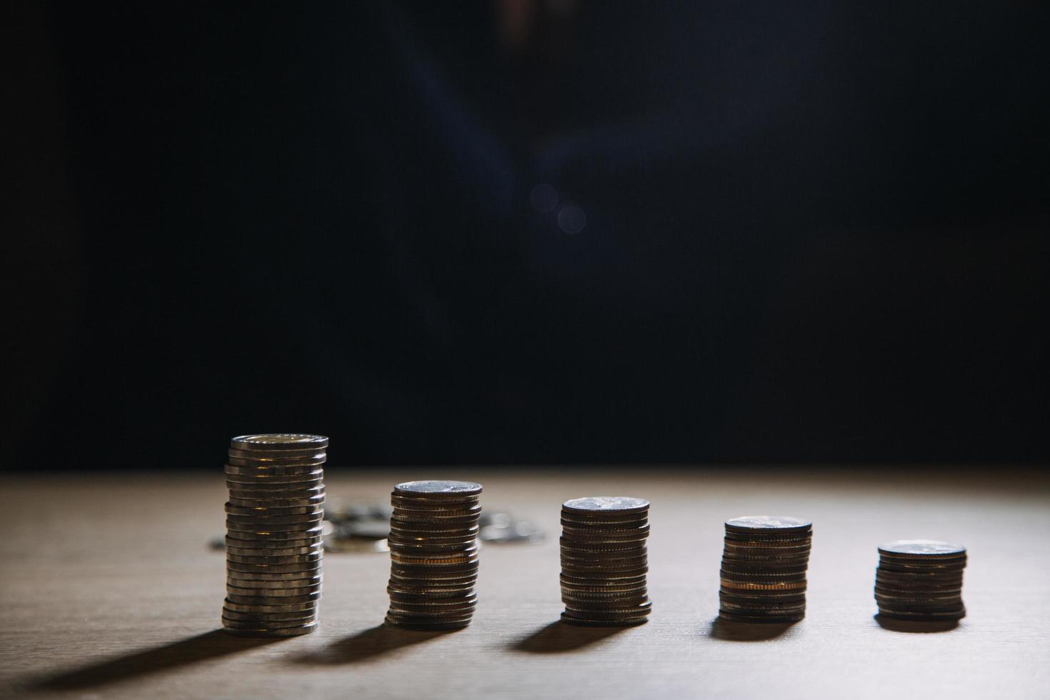 besparing geld hand- zetten munten Aan stack Aan tafel met zonneschijn. concept financiën en accounting foto