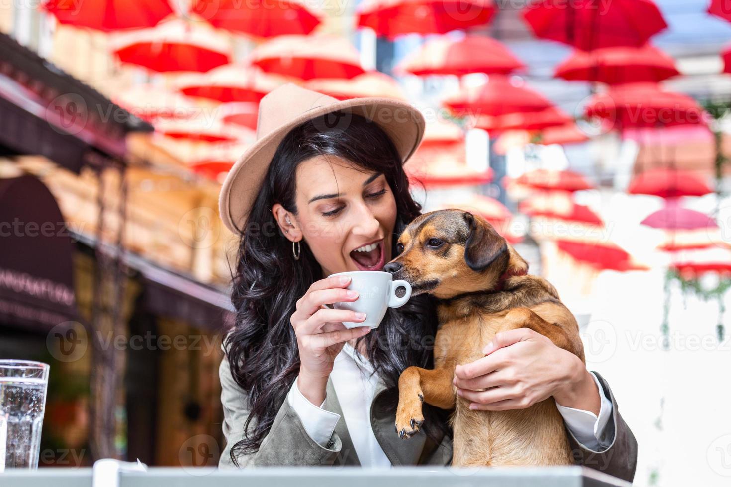jong vrouw met haar hond in huisdier vriendelijk cafetaria. meisje drinken koffie Bij lokaal koffie winkel met haar huisdier hond foto