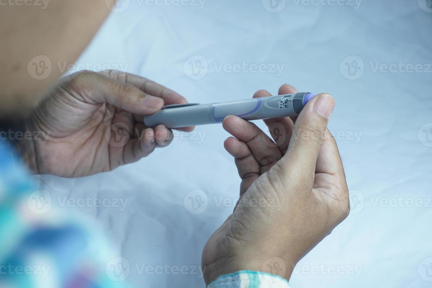 gedeeltelijk wazig afbeelding van Mens Holding insuline pen. medisch uitrusting is gemakkelijk naar zelf injectie foto