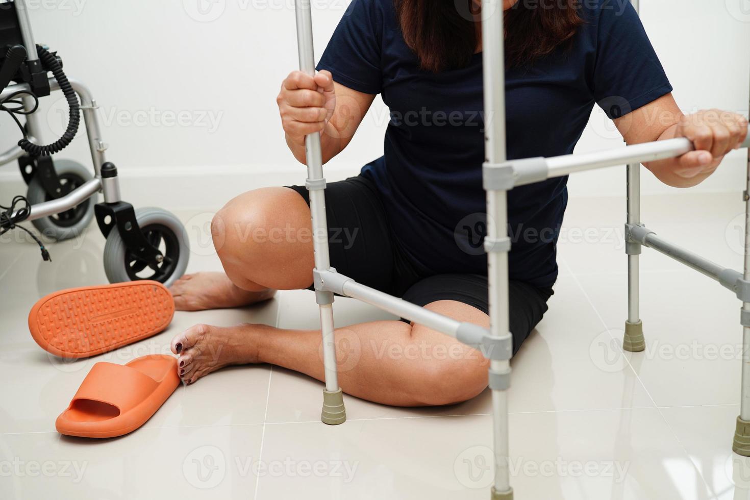 Aziatisch vrouw letsel van vallend naar beneden Aan glad oppervlakken met wandelaar Bij huis. foto