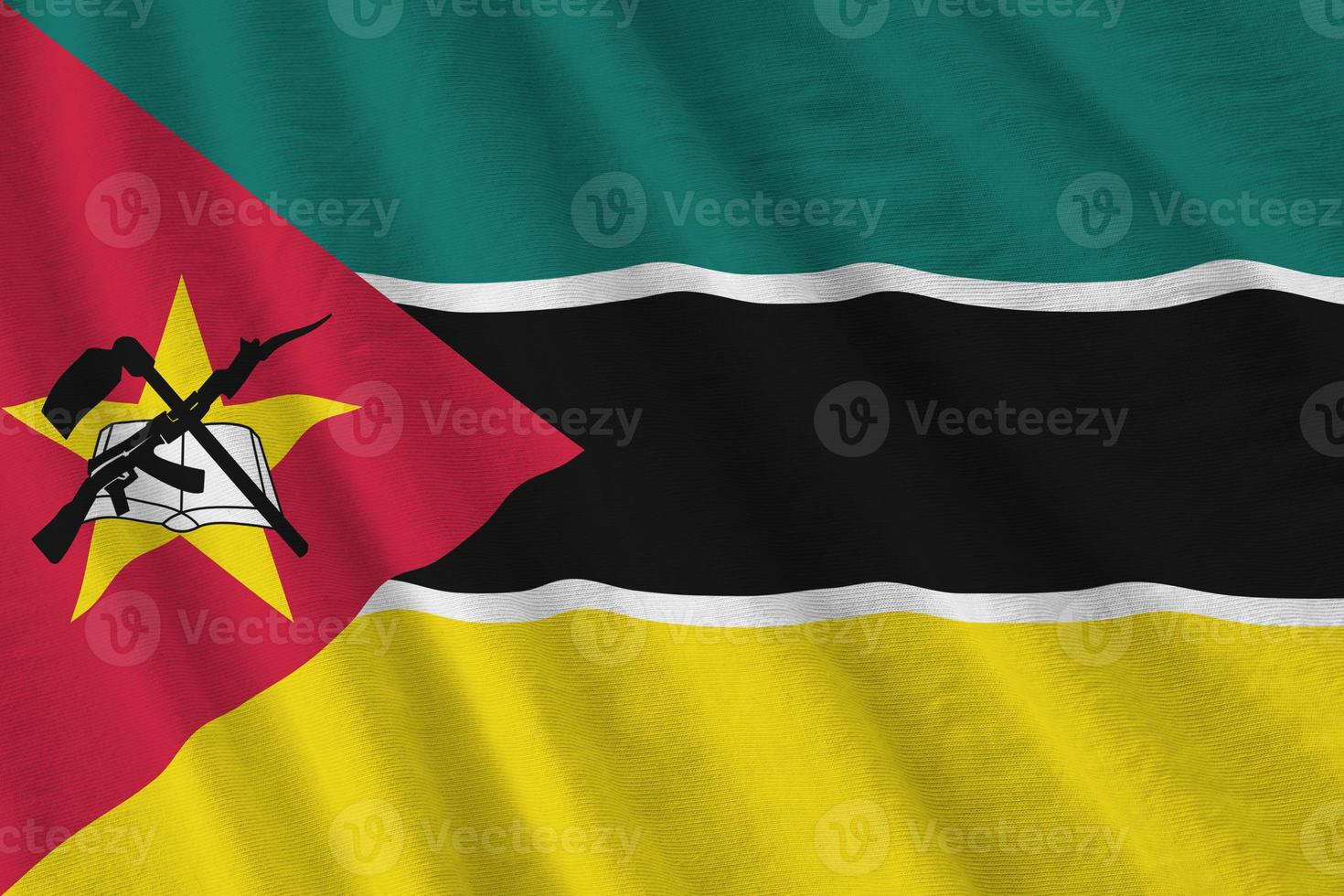 Mozambique vlag met groot vouwen golvend dichtbij omhoog onder de studio licht binnenshuis. de officieel symbolen en kleuren in banier foto