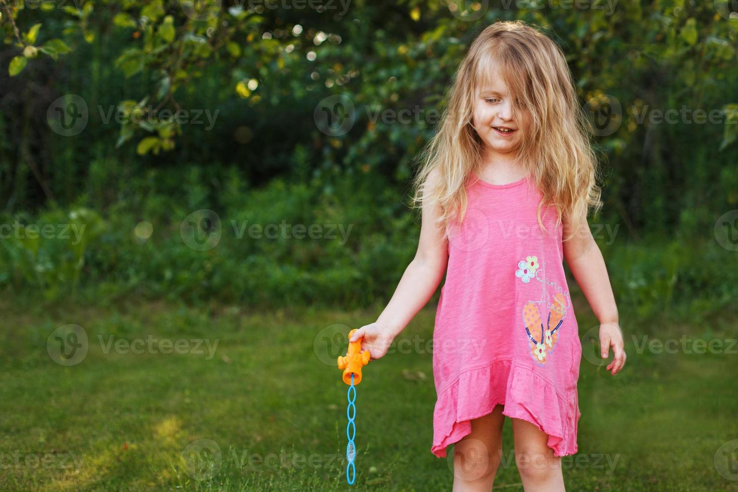 schattig weinig meisje is blazen zeep bubbels foto