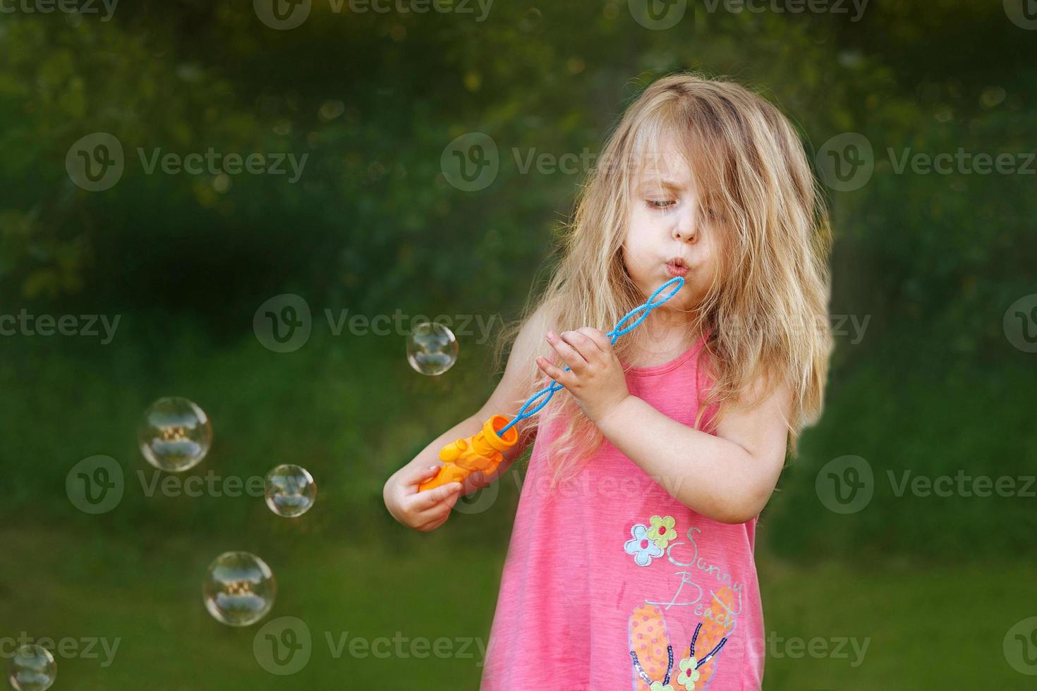 schattig weinig meisje is blazen zeep bubbels foto