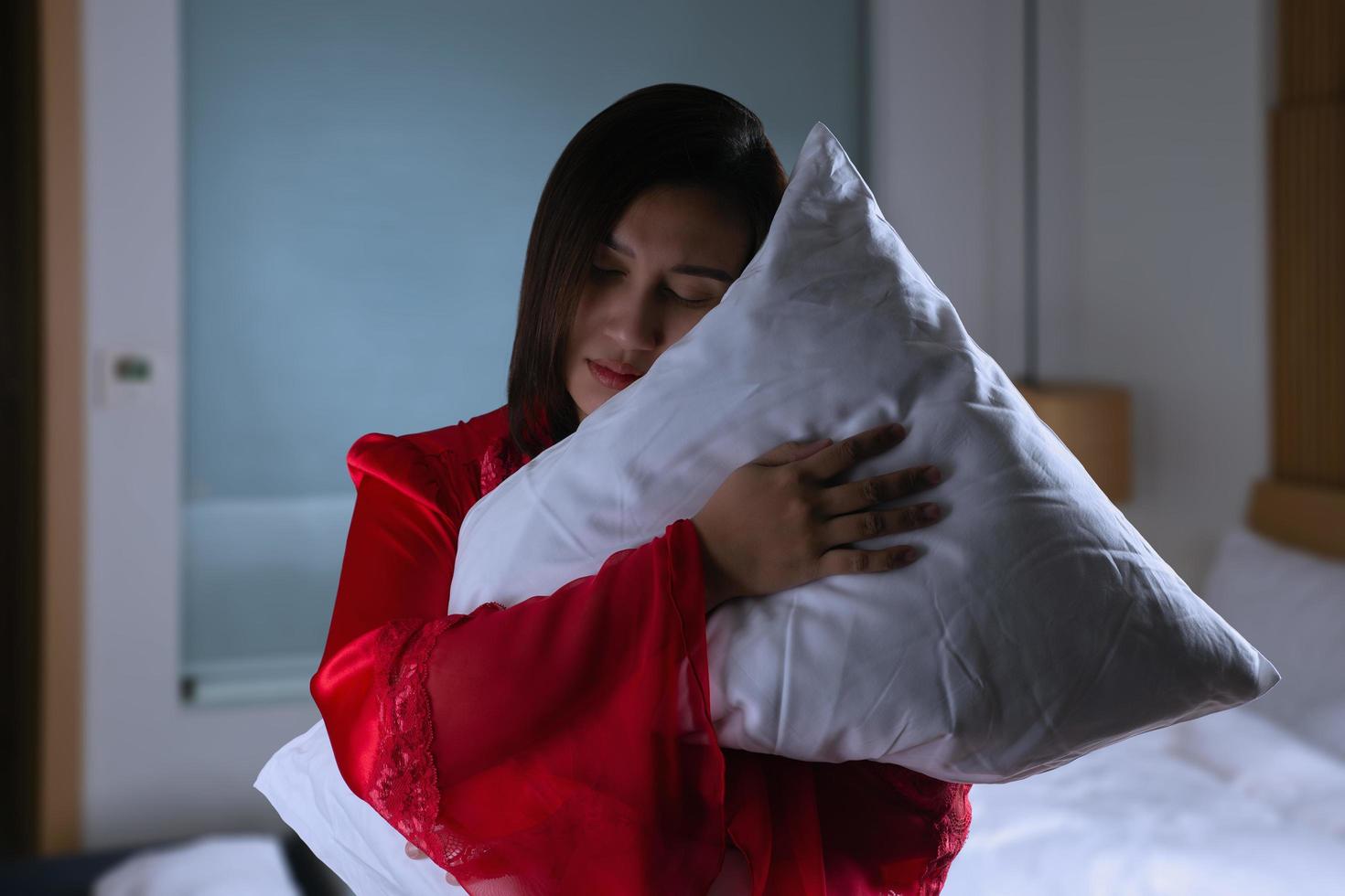 vrouw in satijn nachtkleding en omarmen zacht hoofdkussen foto