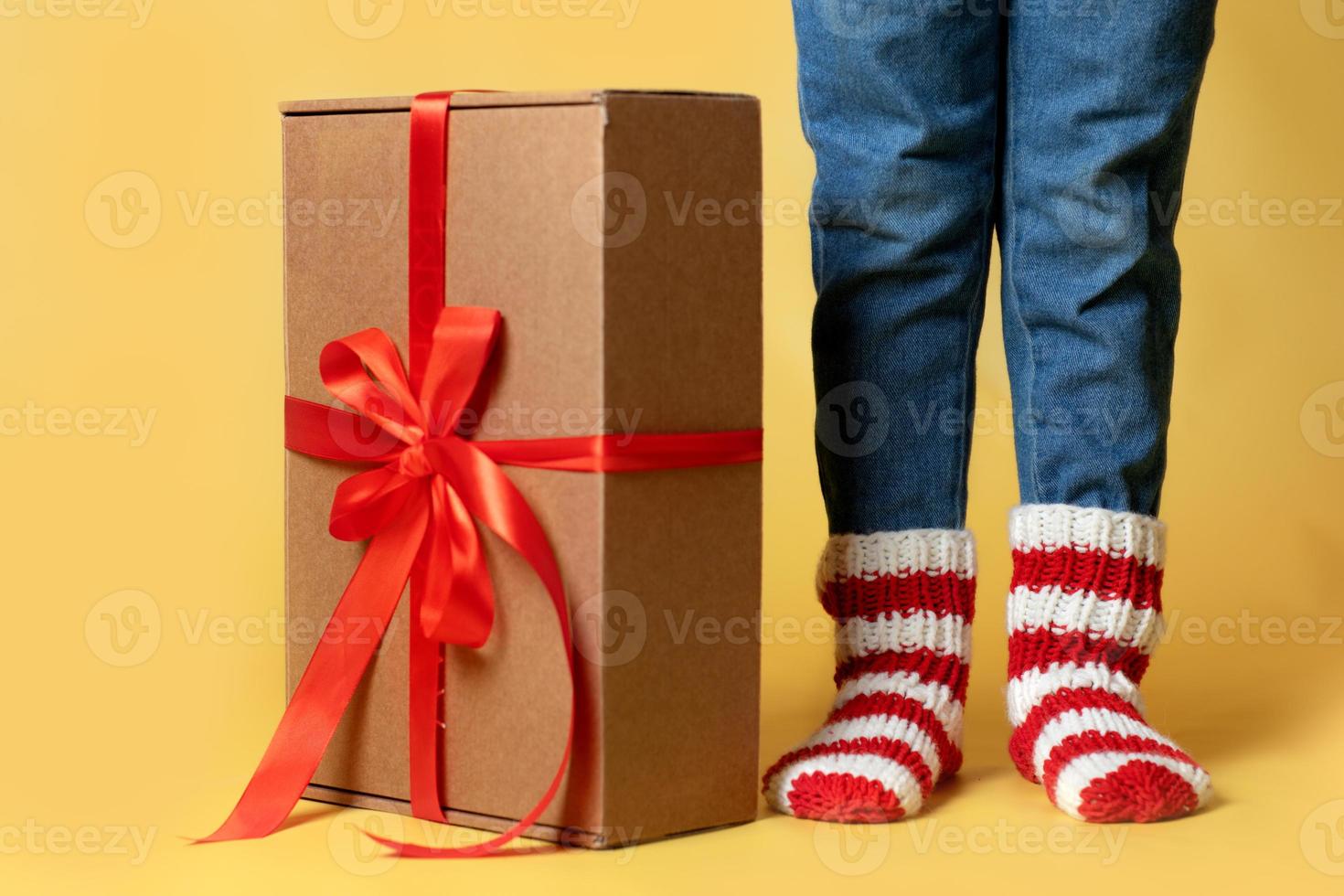 levering Kerstmis cadeaus boodschappen doen ambacht papier doos en geschenk lint presenteert en kind in gebreid sokken geïsoleerd geel achtergrond foto