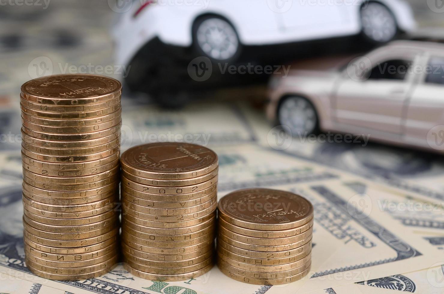 speelgoed- auto in ongeluk Aan een achtergrond van 100 dollar rekeningen en stapels van gouden munten foto