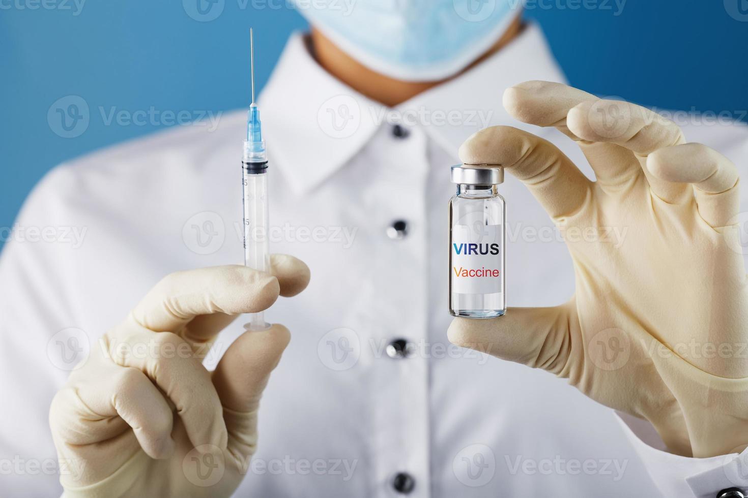 een ampul met de opschrift virus vaccin en een injectiespuit in de handen van een wetenschapper dokter in rubber handschoenen met een vaccin detailopname. foto
