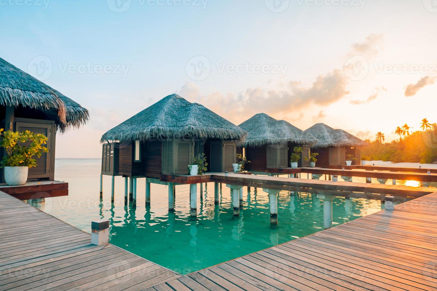 zonsondergang op het eiland Malediven, luxe watervilla's resort en houten pier. mooie lucht en wolken en strandachtergrond voor de zomervakantie en reisconcept foto