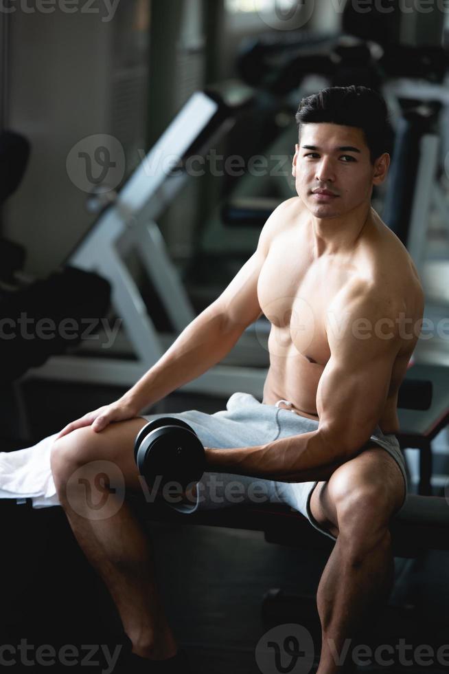 jong Mens training, hijs- met halter naar bouwen spier in geschiktheid Bij Sportschool. foto