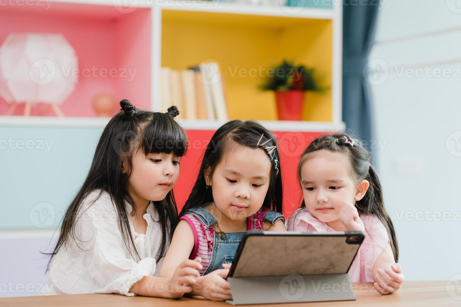 groep van kinderen gebruik makend van tablet in klas, multi-etnisch jong jongens en meisjes gelukkig gebruik makend van technologie voor studie en Speel spellen Bij elementair school. kinderen gebruik technologie voor onderwijs concept. foto