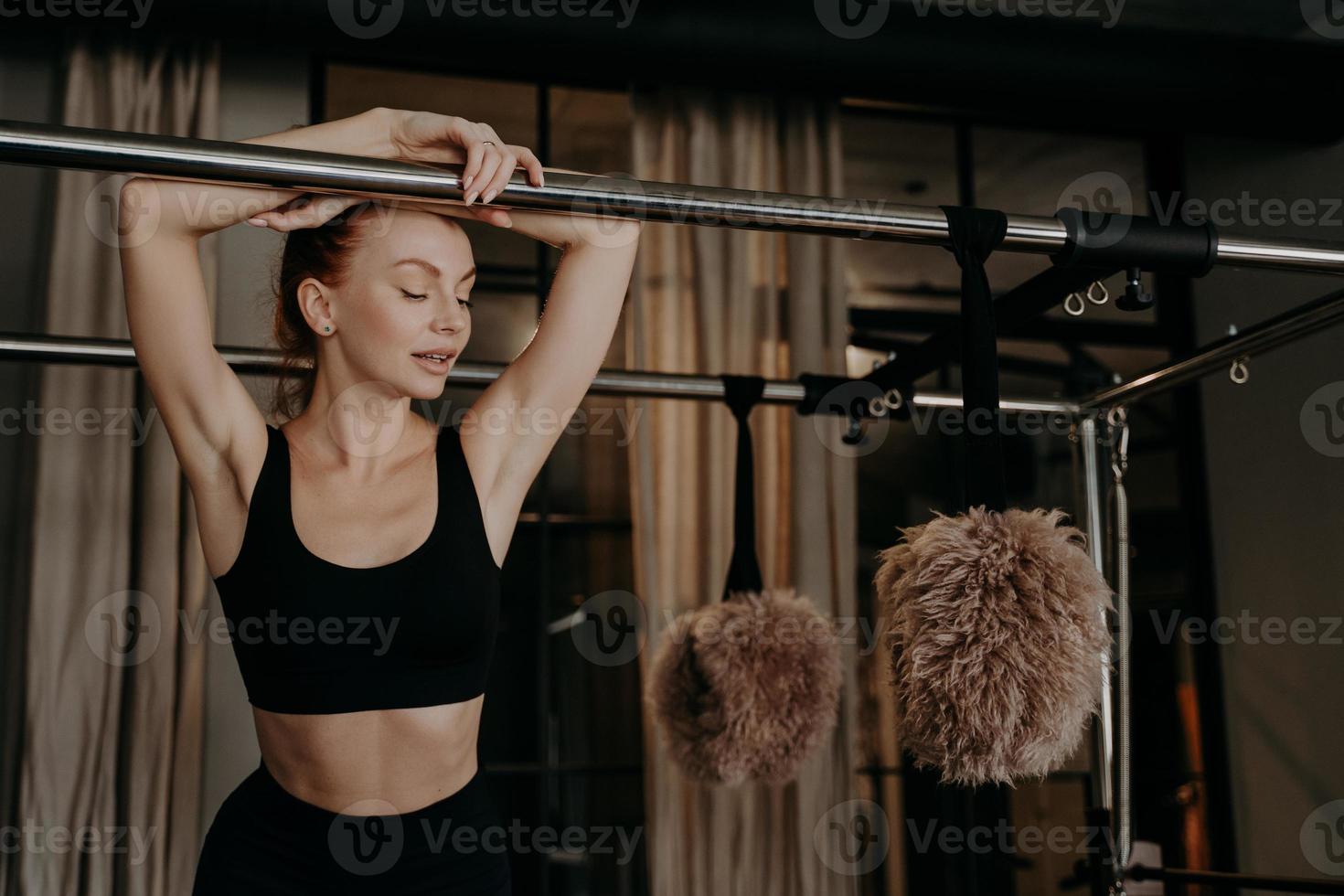 mooie roodharige fitness vrouw ontspannen op pilates cadillac reformer foto