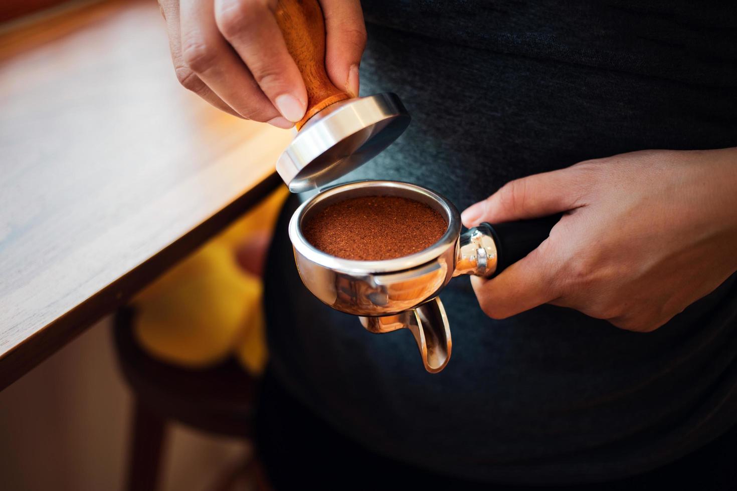 detailopname van hand- barista cafe maken koffie met handleiding persen grond koffie gebruik makend van knoeien Bij de koffie winkel foto