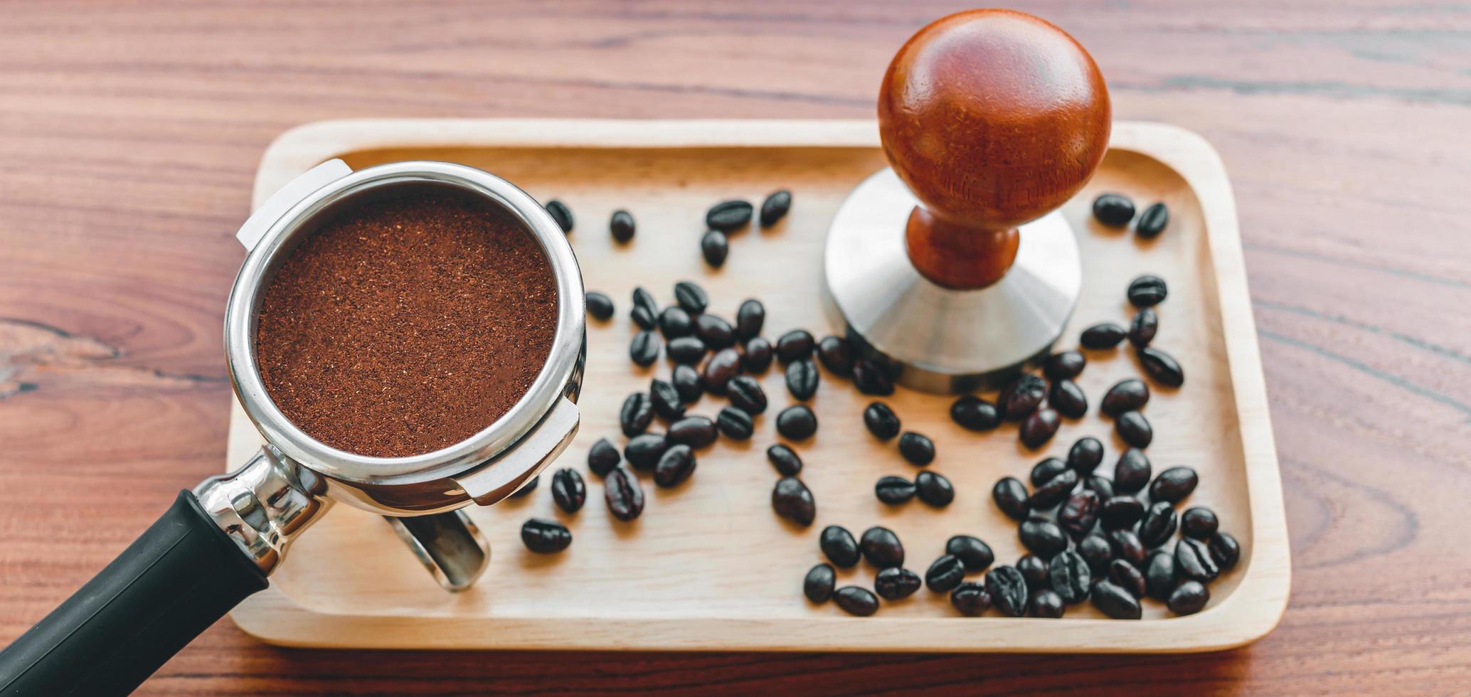 uitrusting van barista koffie gereedschap knoeien en gehumeurd koffie in filterhouder geroosterd koffie bonen Aan houten tafel foto