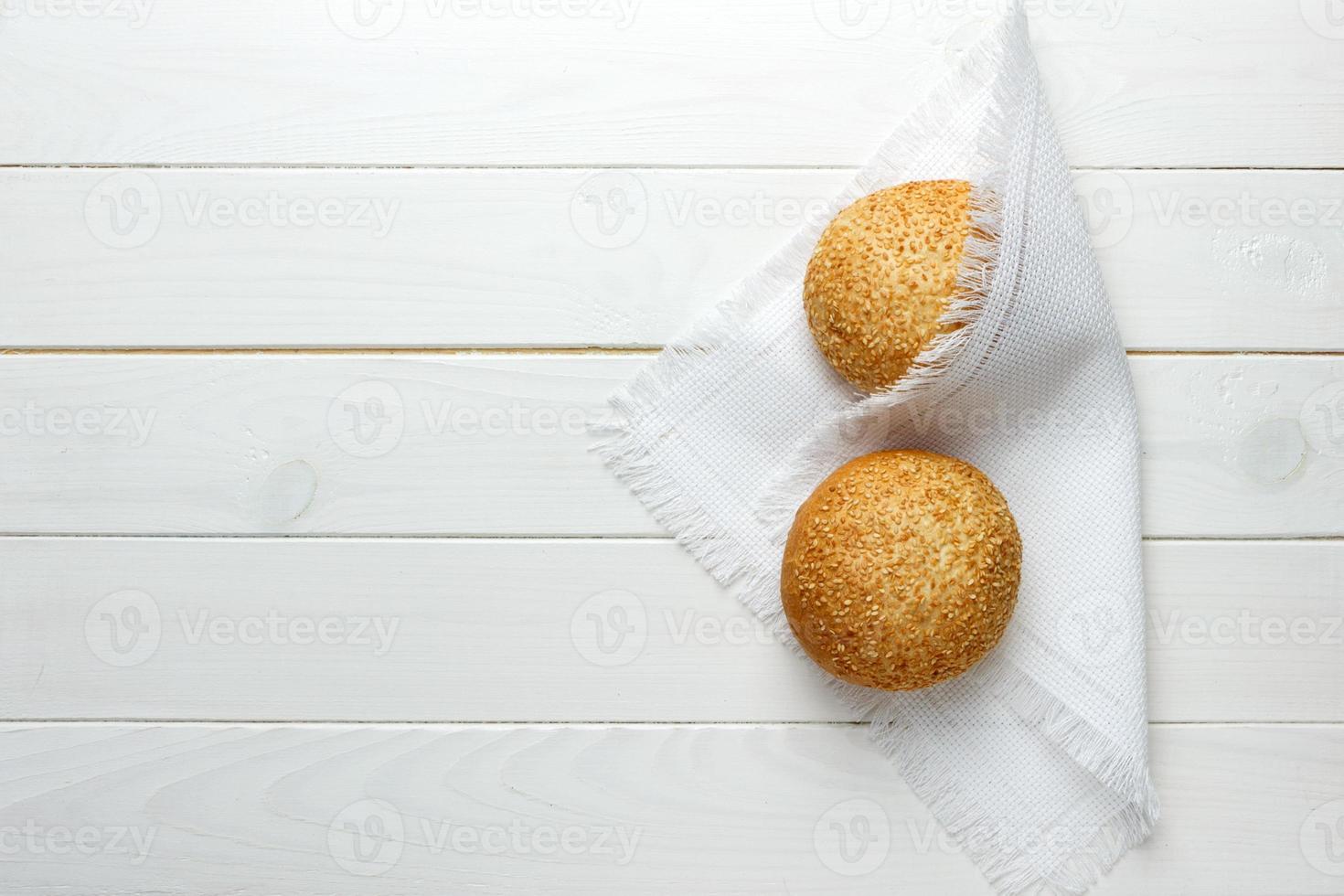 gebakken bun met sesam zaden aan het liegen Aan kleding stof foto