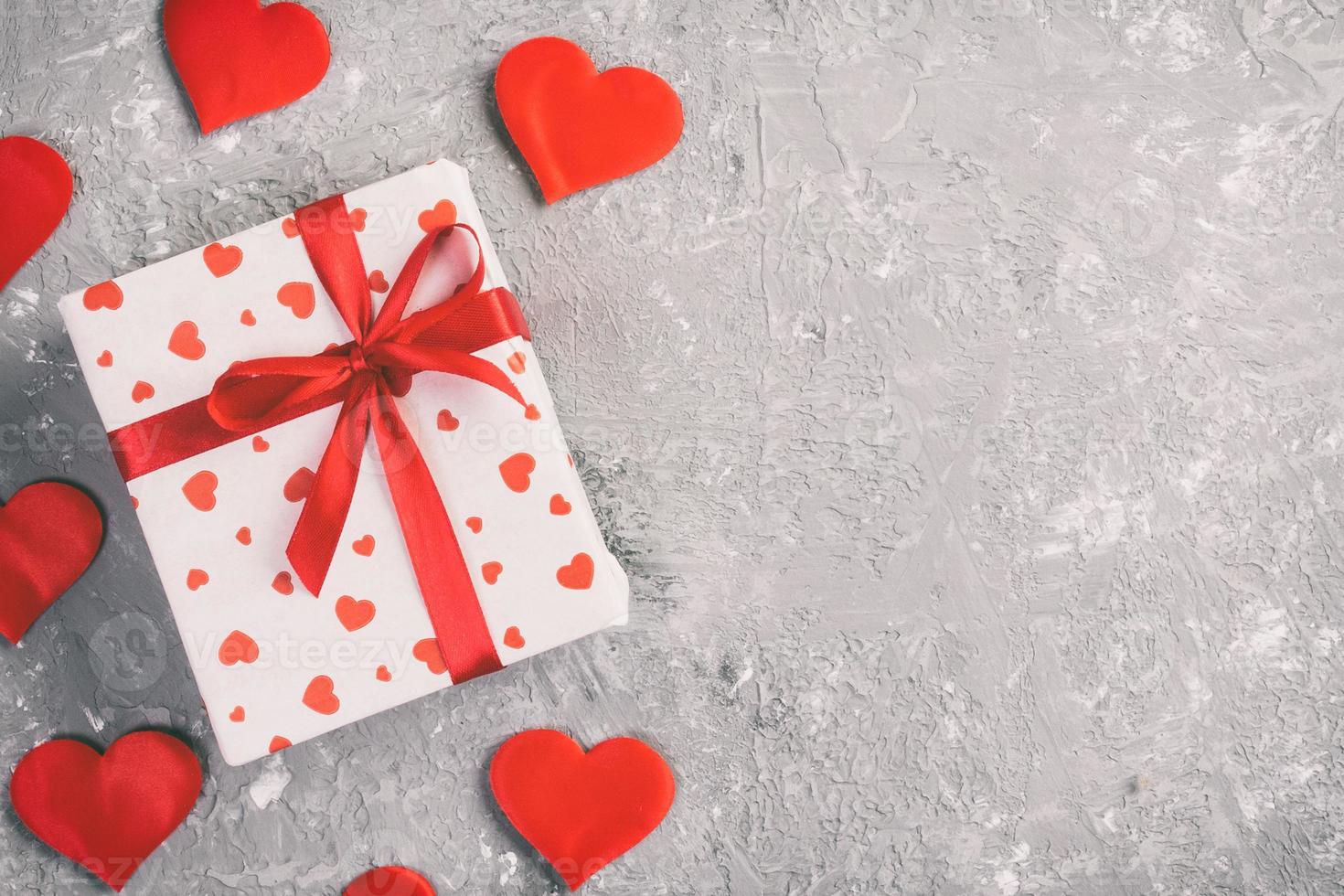 Valentijn of andere vakantie handgemaakt Cadeau in papier met rood harten en cadeaus doos in vakantie wikkel. Cadeau doos van geschenk Aan grijs cement tafel top visie met kopiëren ruimte, leeg ruimte voor ontwerp foto