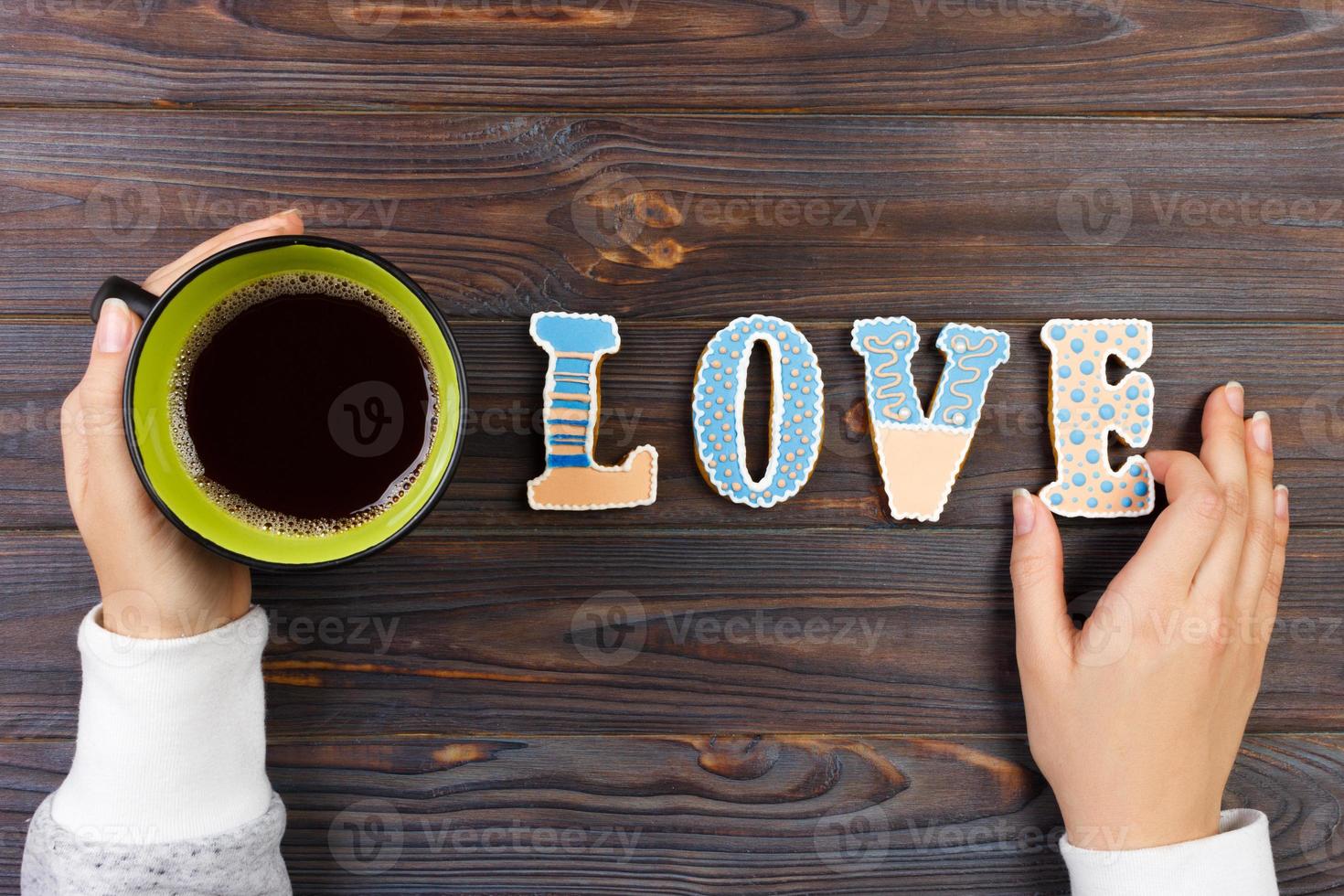 vrouw handen met koffie en hart vormig koekjes Aan houten tafel, top visie. liefde concept. koekjes liefde brief foto