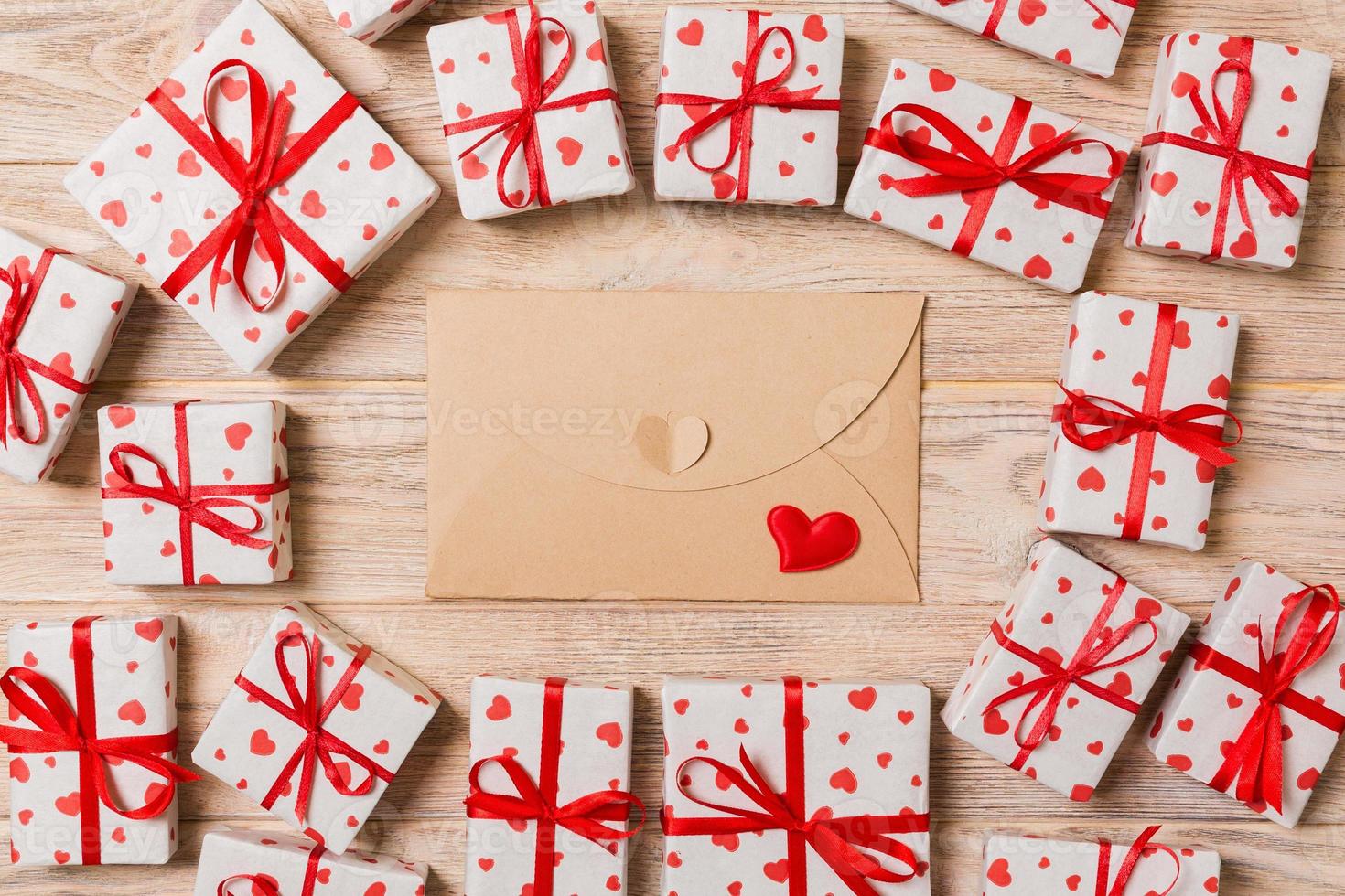 valentijnsdag dag romantisch achtergrond. envelop kaart met geschenk dozen en hart Aan een houten achtergrond foto