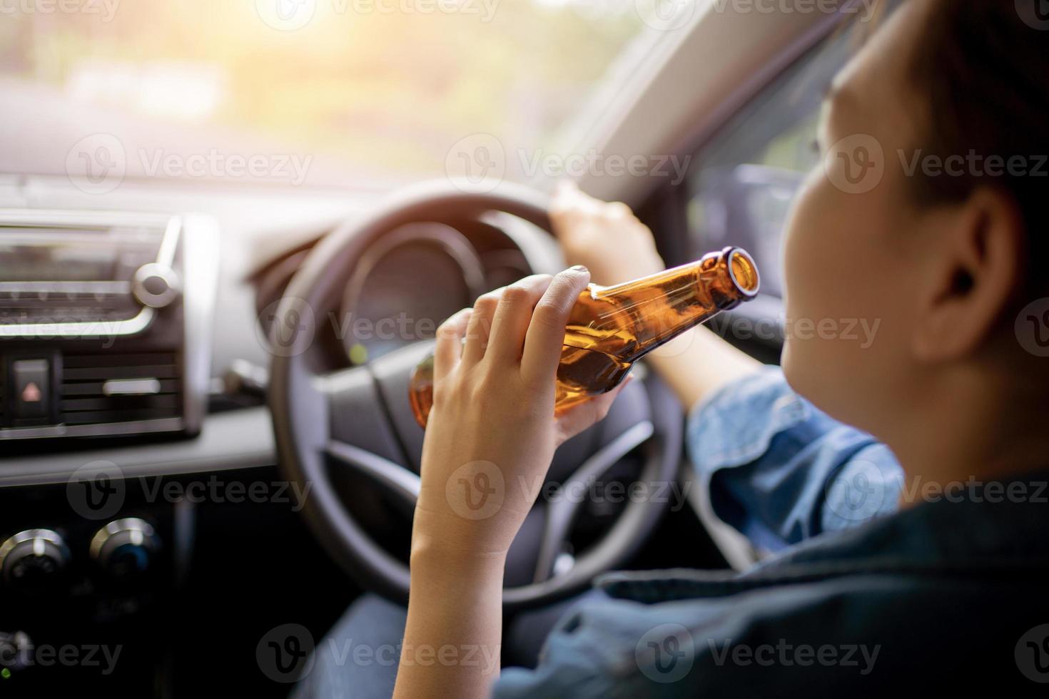 dichtbij omhoog van bestuurder en drinken alcohol welke dronken jong vrouw het rijden een auto met een fles van bier, dronken het rijden concept, niet doen drinken en rit concept. foto