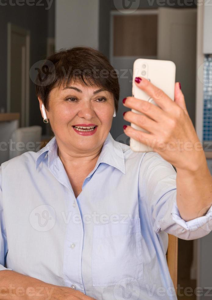 verticaal banier van ouderling vrouw gebruik makend van smarphone voor communicatie met haar kinderen, vrienden en andere familie. video telefoontje toepassing foto