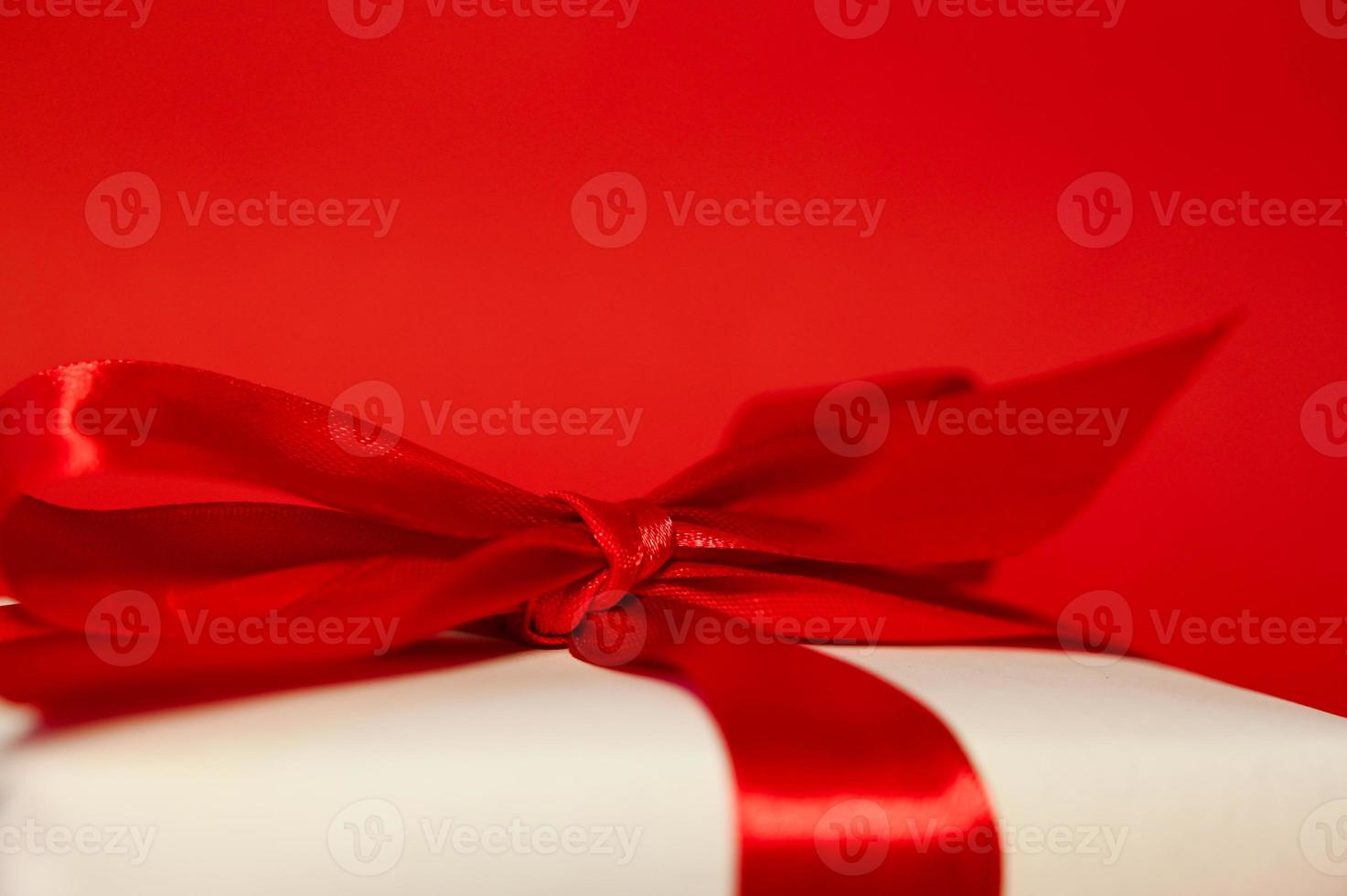 geschenk doos verpakt in wit papier met een rood boog. plaats voor tekst.selectief focus foto