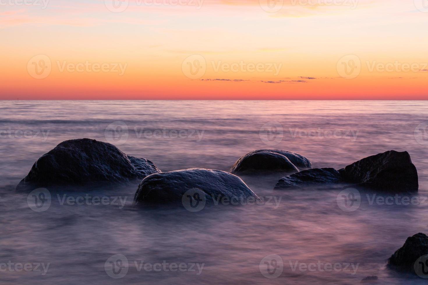 stenen Aan de kust van de Baltisch zee Bij zonsondergang foto