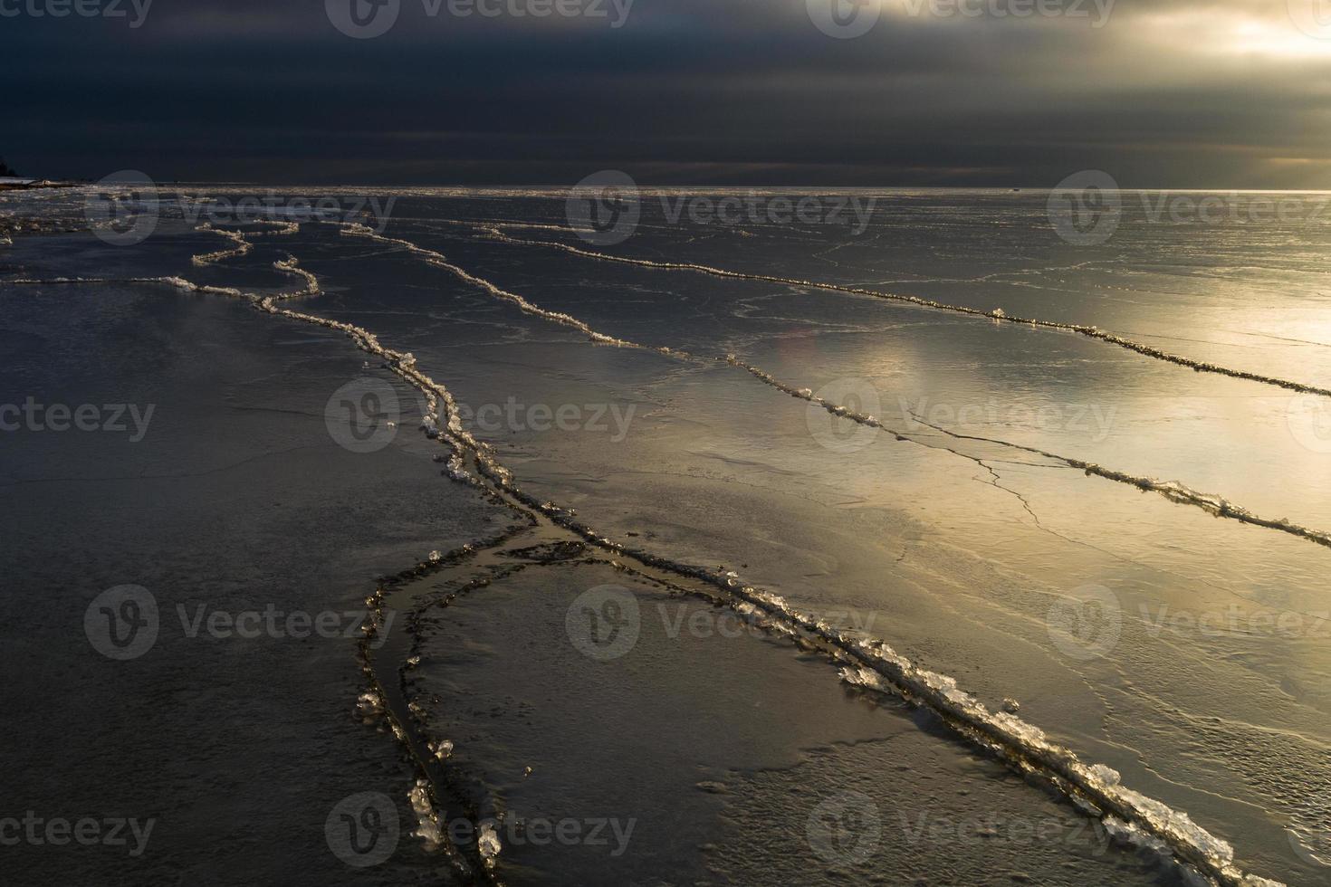 Baltisch zee kust met steentjes en ijs Bij zonsondergang foto