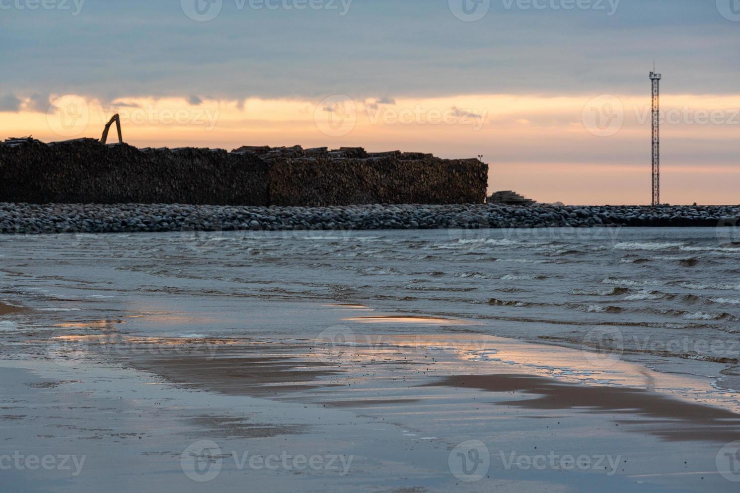 Baltisch zee kust met steentjes en ijs Bij zonsondergang foto
