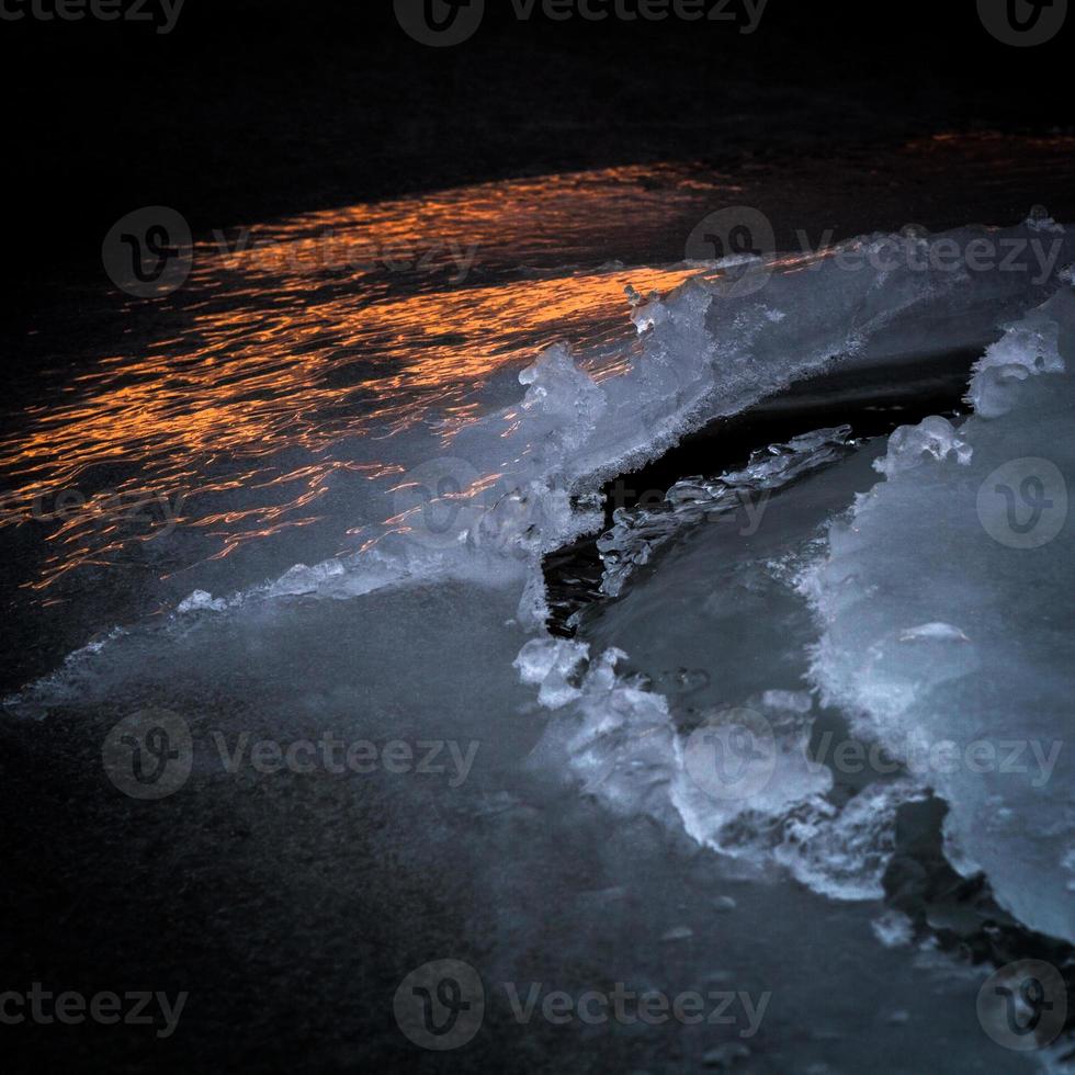 Baltisch zee kust met steentjes en ijs Bij zonsondergang foto