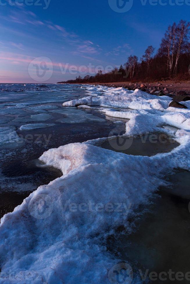 Baltisch zee kust in winter met ijs Bij zonsondergang foto