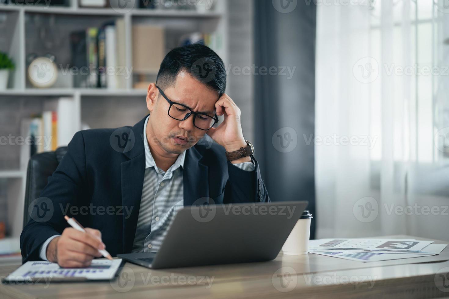 Aziatisch bedrijf Mens slijtage bril en hand- over- hoofd hebben stressvol depressie verdrietig tijd terwijl werken Aan laptop Bij huis. depressie Mens verdrietig serie werken van huis. werken Bij overal concept. foto
