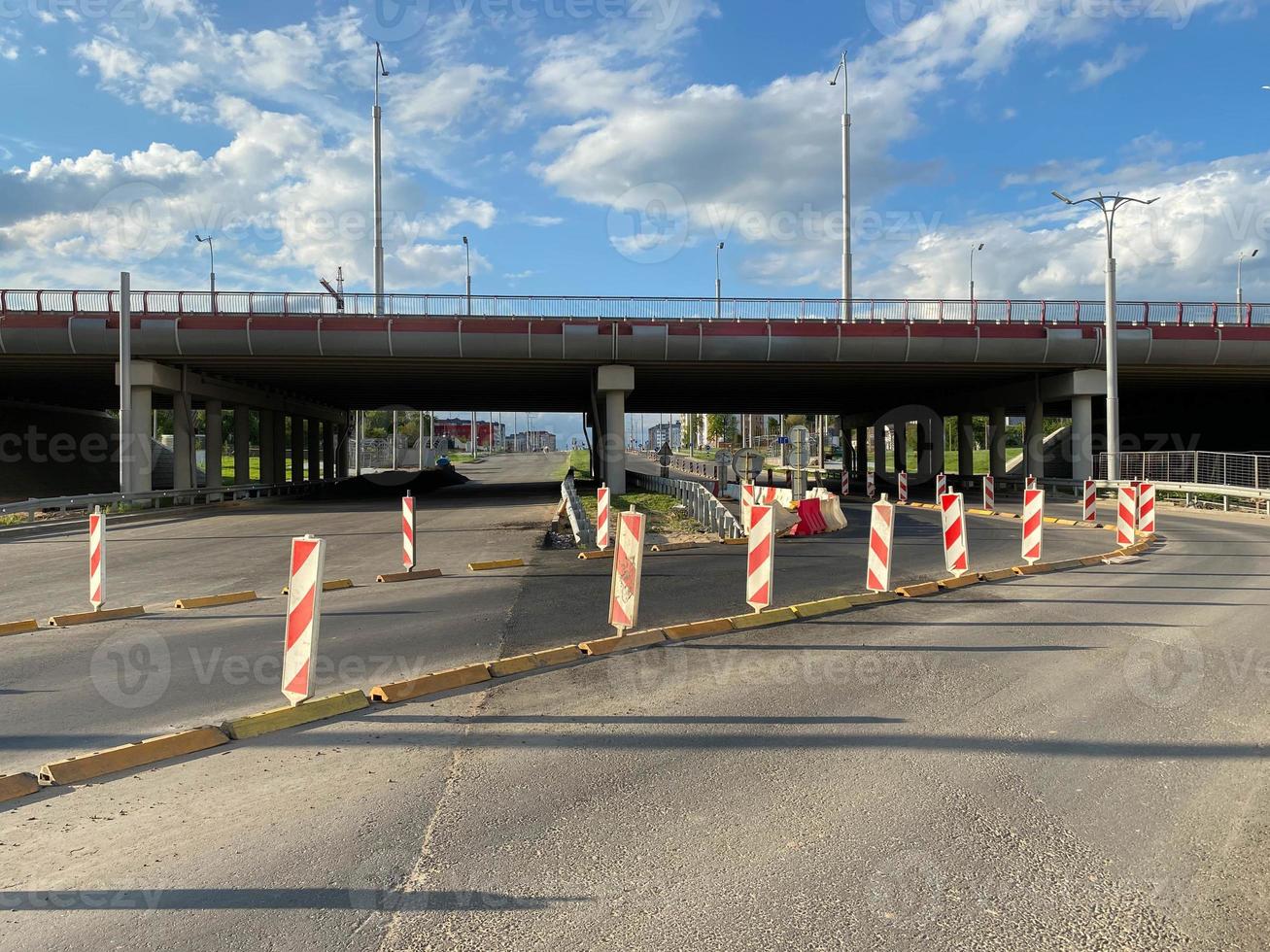 reparatie en bouw van een weg met tijdelijk weg tekens en kegels Aan de achtergrond van een groot snelweg brug in een groot stad foto
