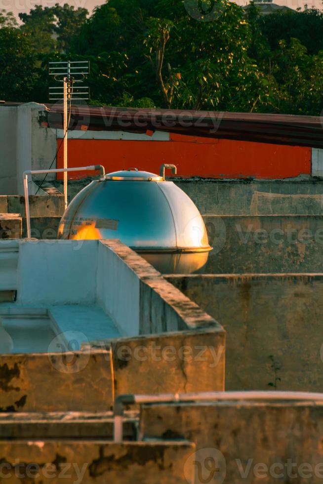 een water tank Aan de dak met de reflectie van de avond licht foto