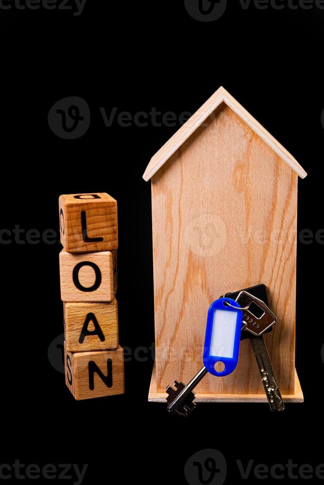 houten huis mockup met huis sleutels, houten kubussen met woorden huur uitverkoop , kopen en lening. Aan zwart achtergrond foto