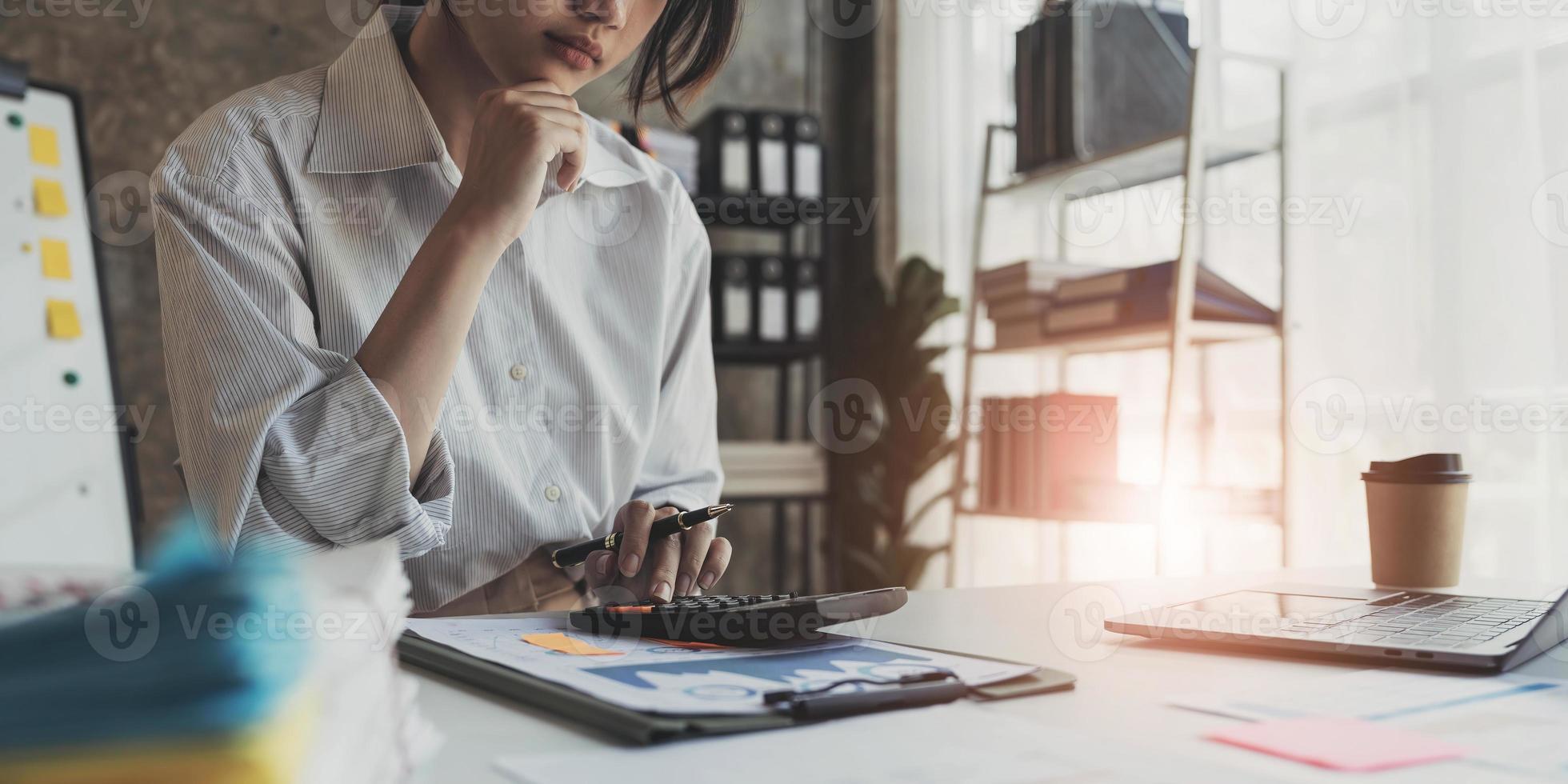 zakenvrouw die rekenmachine gebruikt om wiskunde te financieren op houten bureau in kantoor en zakelijke achtergrond, belasting, boekhouding, statistiek en analytisch onderzoeksconcept foto