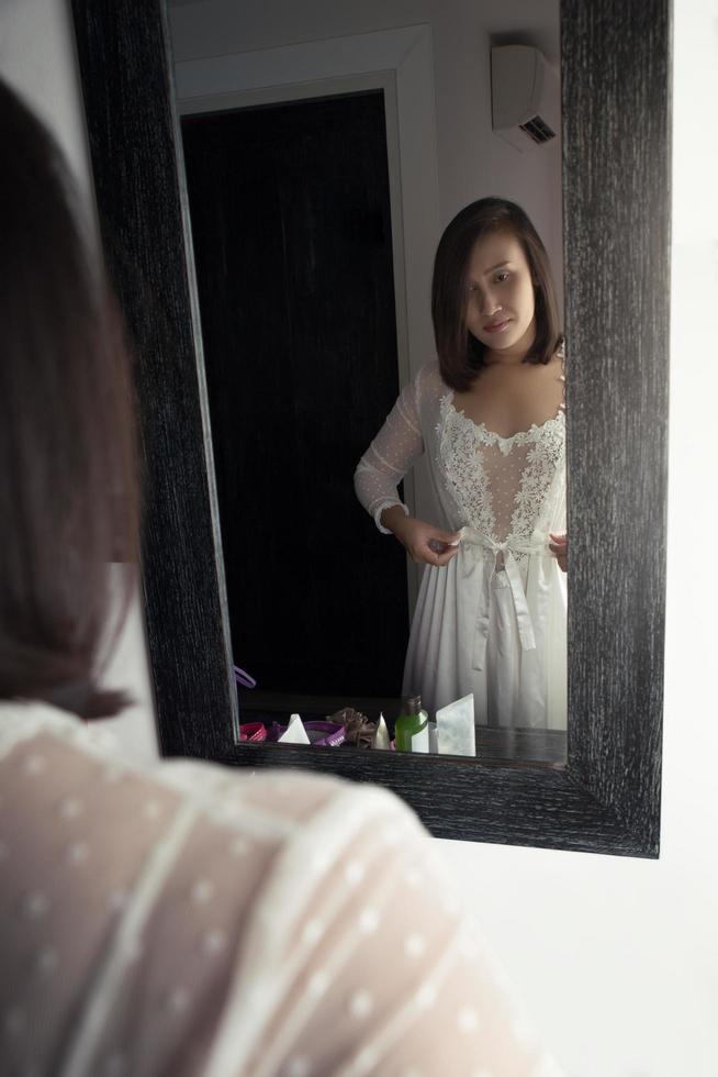 een vrouw zetten Aan haar wit nachthemd foto