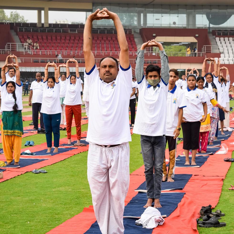 nieuw Delhi, Indië, juni 21 2022 - groep yoga oefening sessie voor mensen Bij Yamuna sport- complex in Delhi Aan Internationale yoga dag, groot groep van volwassenen Bijwonen yoga klasse in krekel stadion foto