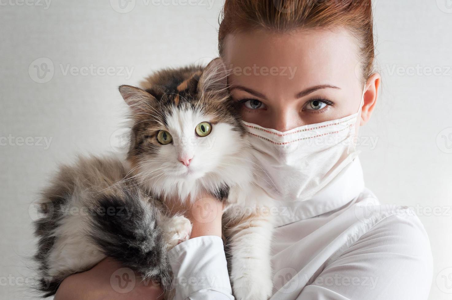 portret van een meisje met een medisch masker. ze houdt een huiskat vast. detailopname foto