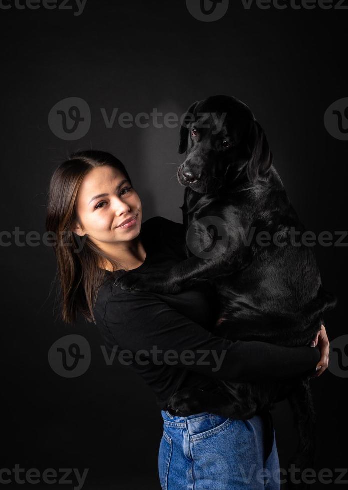 een meisje houdt een labrador retriever-hond in haar armen. foto