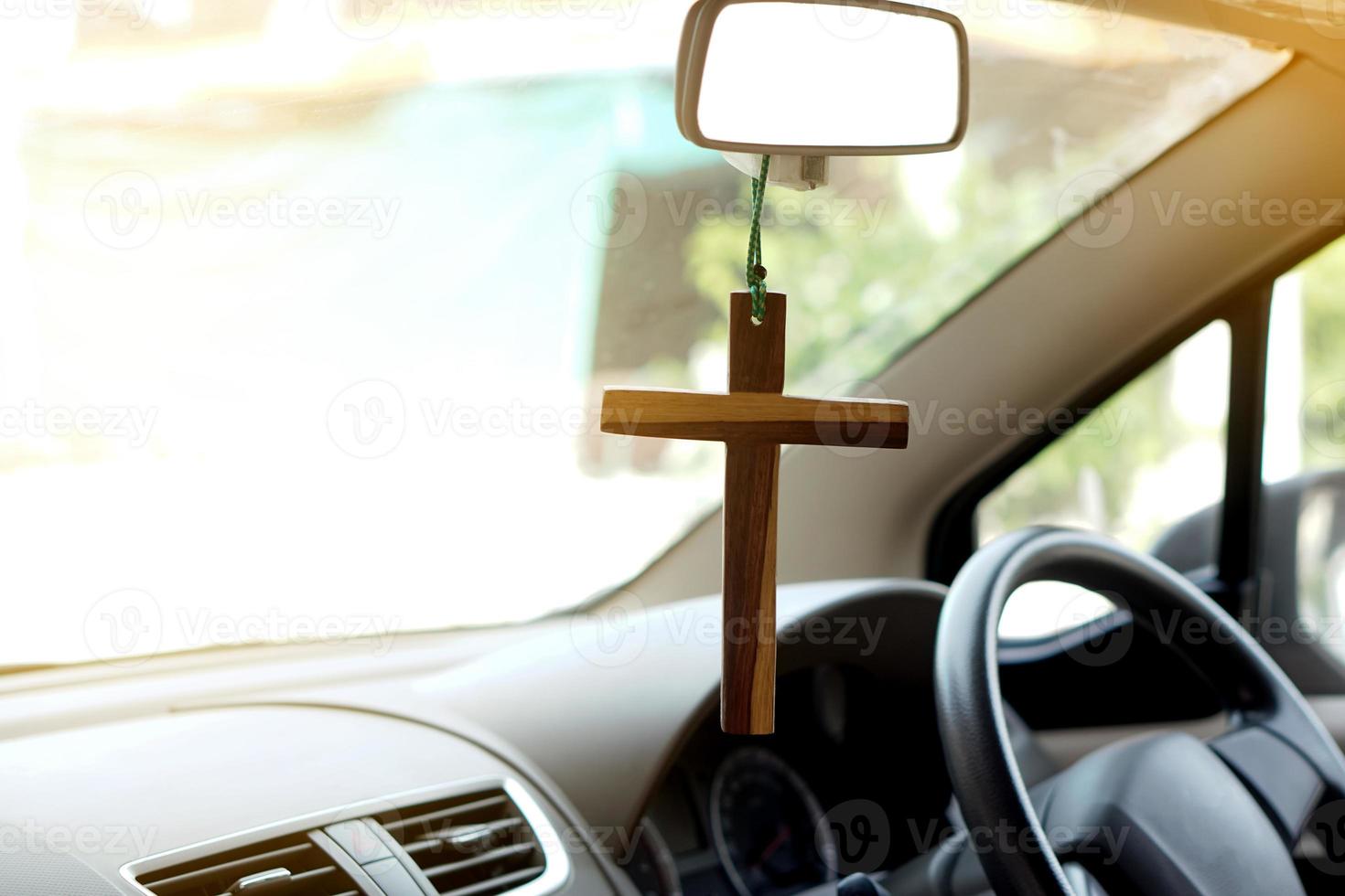 detailopname houten kruisbeeld hangen in voorkant stuurinrichting wiel en troosten van de auto. concept, talisman, amulet naar voorkomen ongelukken. geloof, geloof, heilig in god naar beschermen wanneer het rijden. foto