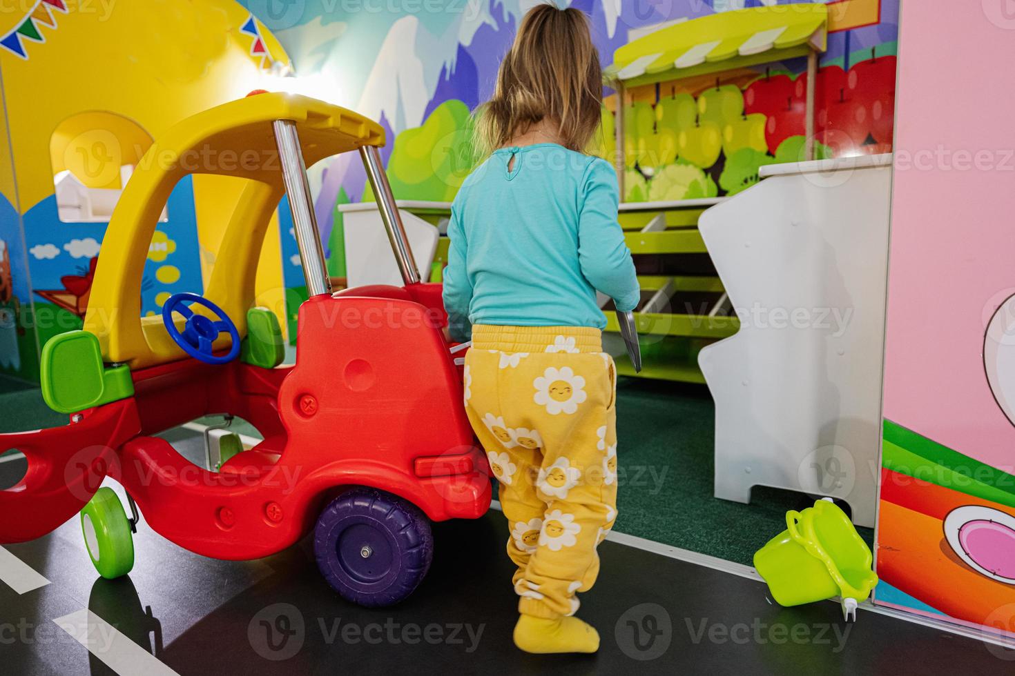 kinderen spelen Bij binnen- Speel centrum speelplaats , meisje in speelgoed- auto. foto