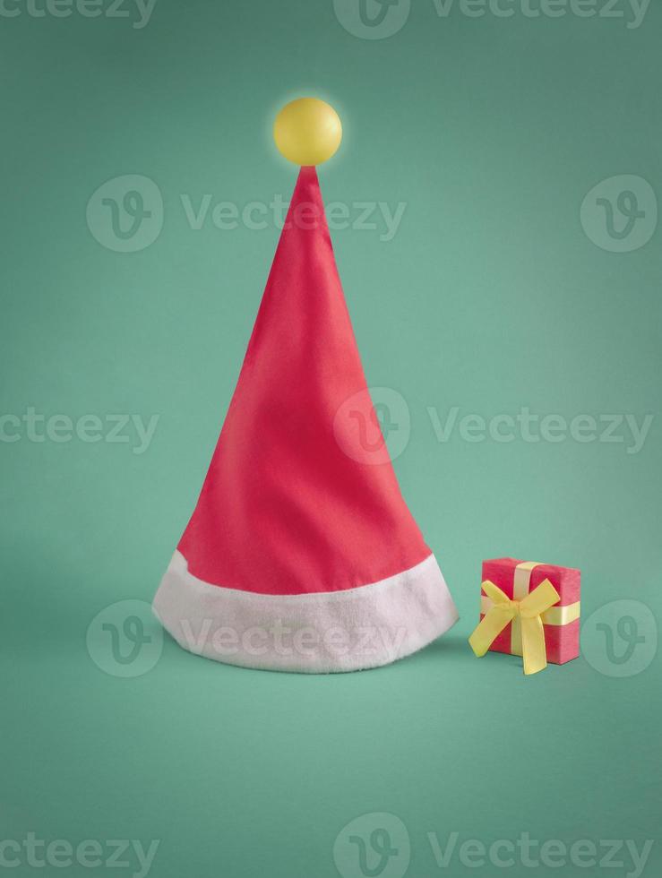 santa's hoed met gloeiend lamp Aan de top. creatief minimaal Kerstmis concept. levendig groen en rood kleuren. foto