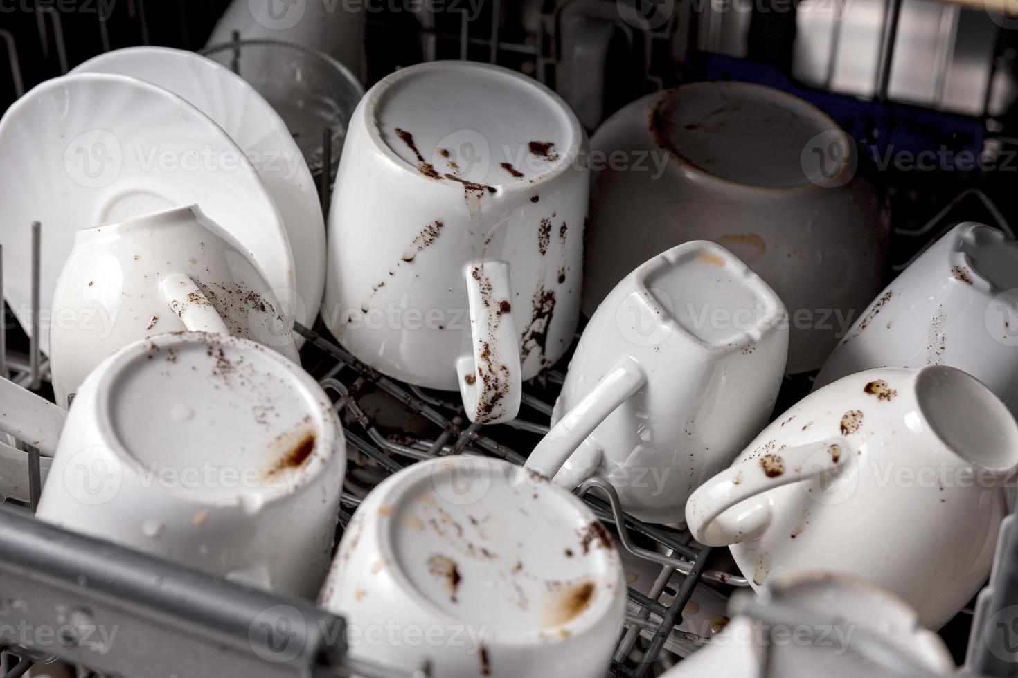 ongewassen, vuil gerechten in afwasmachine. knoeien in de keuken. vuil keukengerei, borden en mokken. rommelig servies. dichtbij omhoog visie. foto