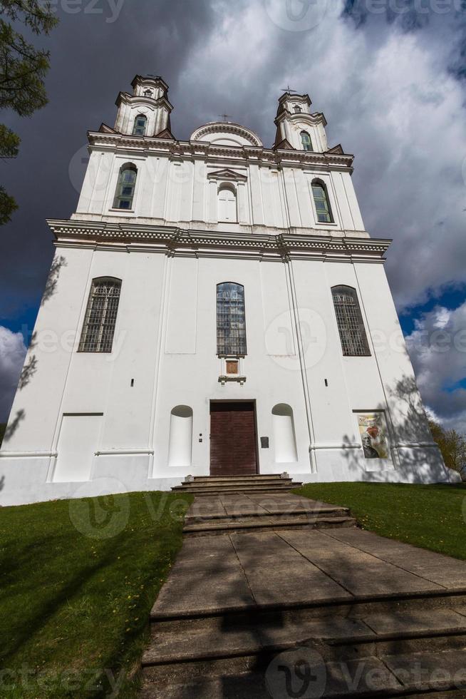 een wit Katholiek kerk Aan een zomer dag met donker wolken in de achtergrond foto