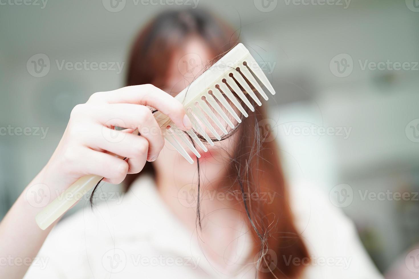 aziatische vrouw heeft een probleem met lang haarverlies, hecht zich aan de kamborstel. foto