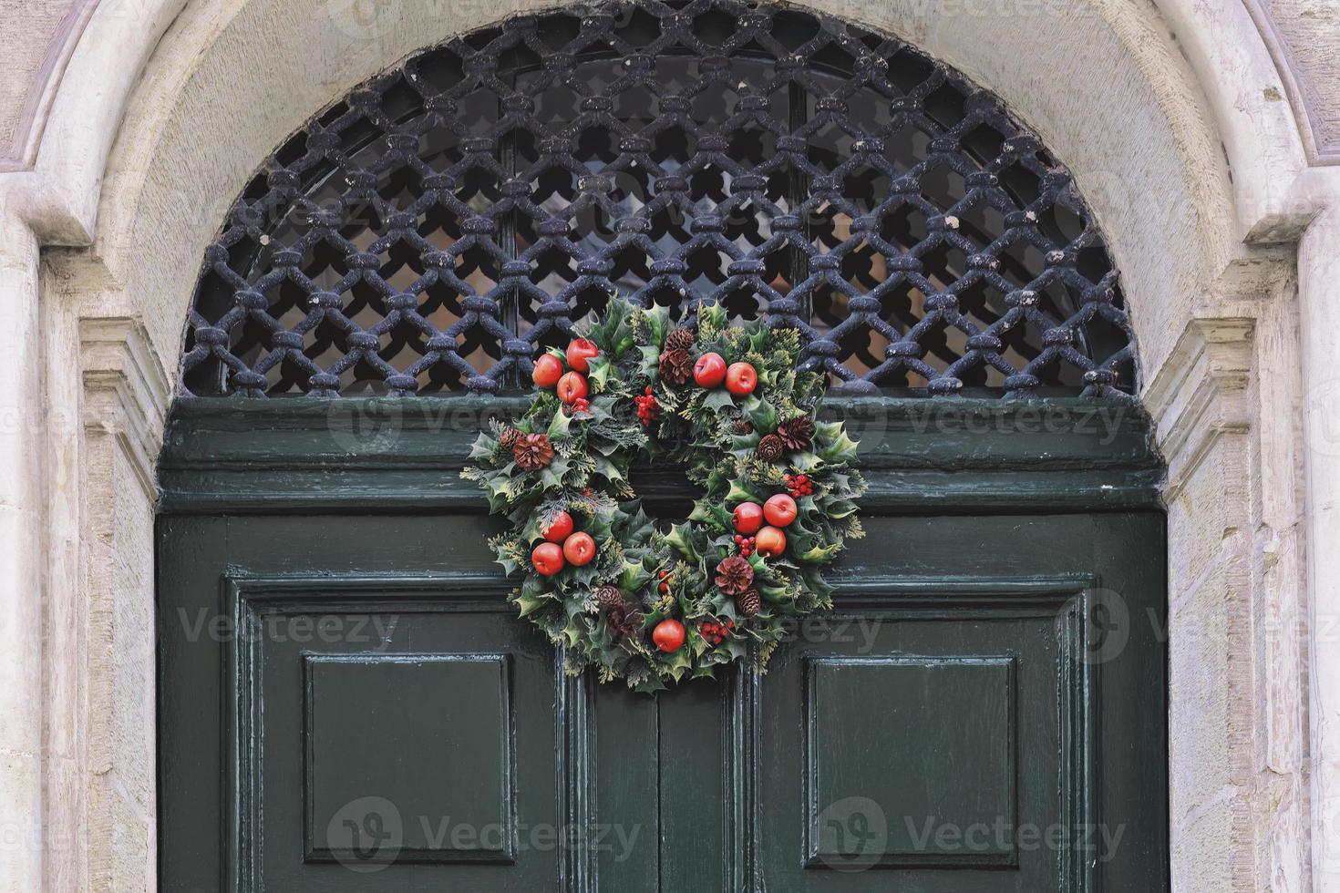 traditioneel groen en rood Kerstmis krans hangende Aan Ingang deur van huis foto