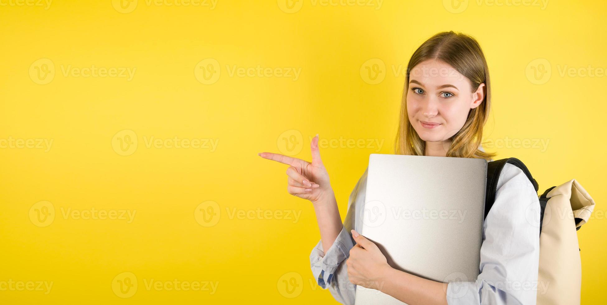 profiel studio schot wat? gelukkig vrouw leerling Holding laptop en richten Bij leeg ruimte Aan geel achtergrond.copyspace banier foto