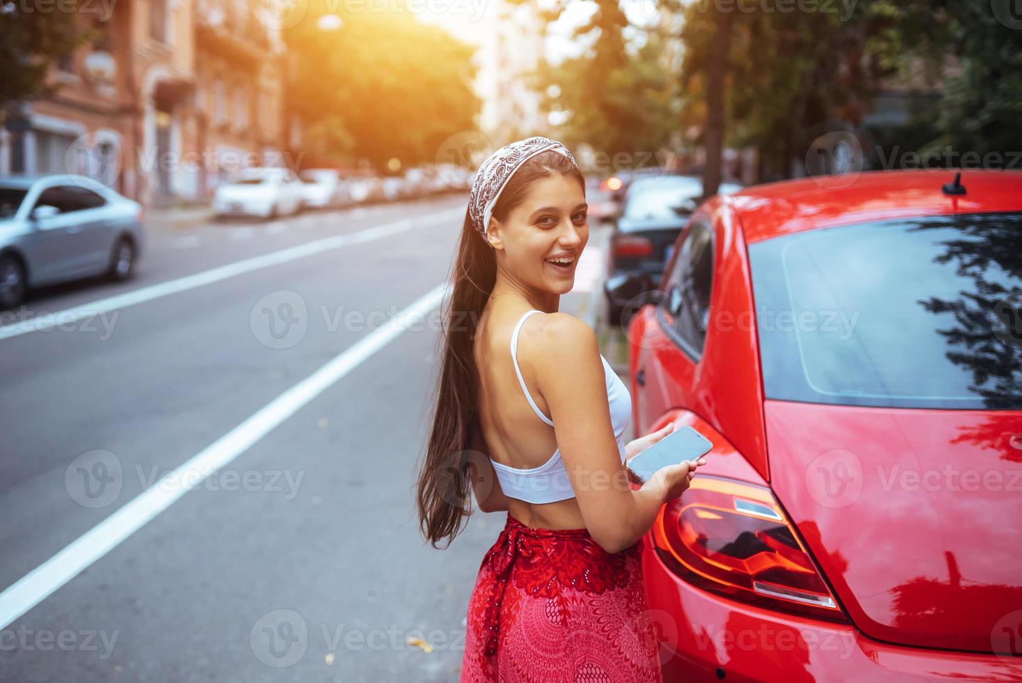portret van mooi Kaukasisch vrouw staand tegen nieuw rood auto foto