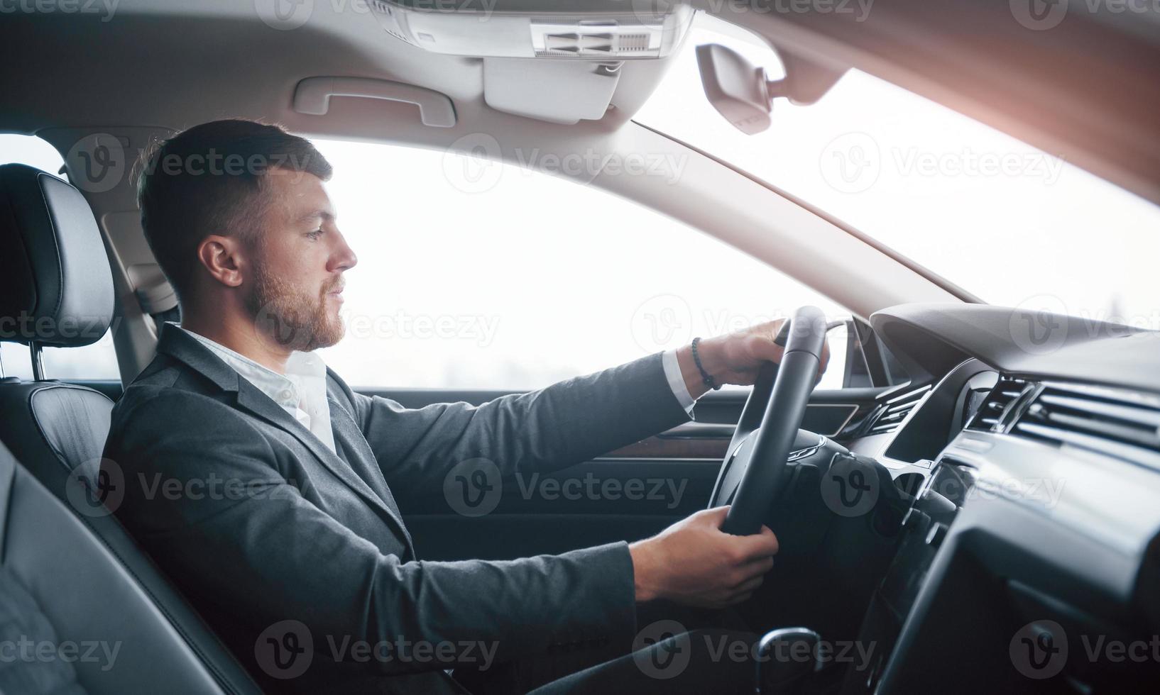 schitterende verlichting. moderne zakenman die zijn nieuwe auto in de autosalon probeert foto